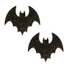 Two black bat-shaped pasties on a white background