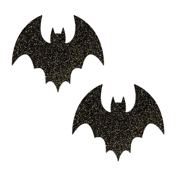 Two black bat-shaped pasties on a white background