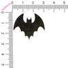 Black glittery bat shape with a ruler for scale on a white background