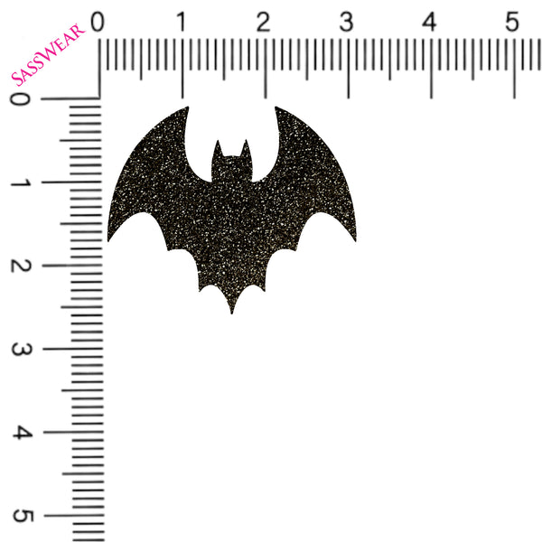 Black glittery bat shape with a ruler for scale on a white background
