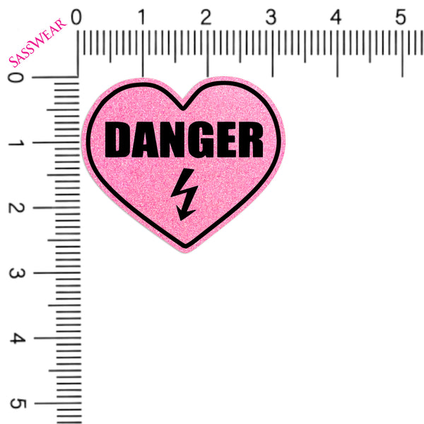 Pink heart-shaped pasties with 'DANGER' text on a white background with a ruler for scale.
